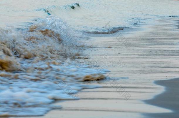 波浪旋转的在海滨越过棕色的海滩沙
