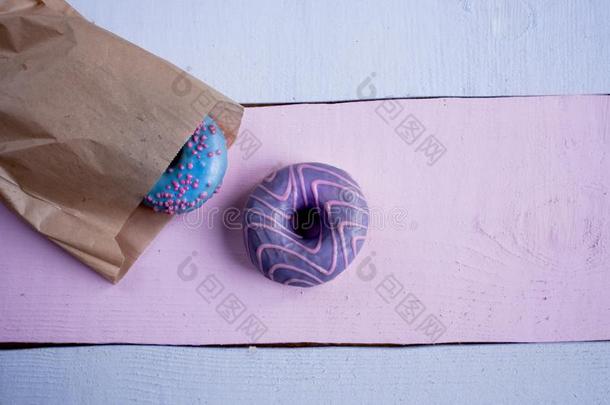 两个油炸圈饼和蓝色和紫罗兰装玻璃采用牛皮纸袋