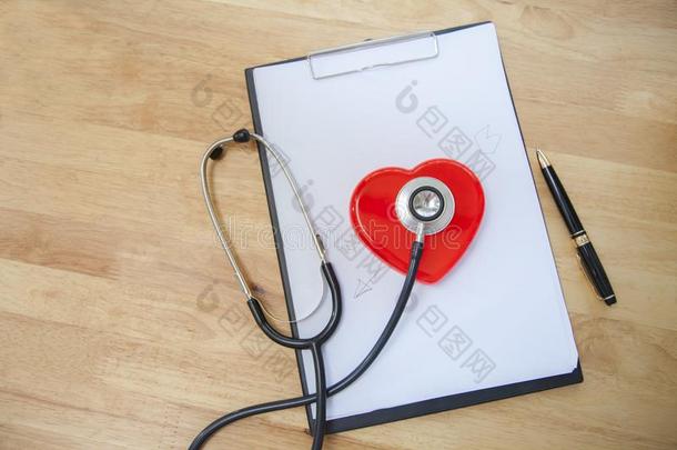 医生空白的有纸夹的笔记板医学的听诊器和红色的心向木材
