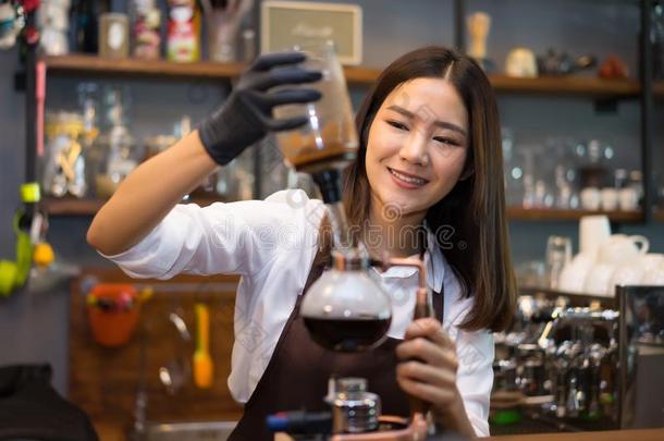 漂亮的年幼的女人高加索人咖啡馆准备咖啡的员工准备咖啡豆吸水管移动