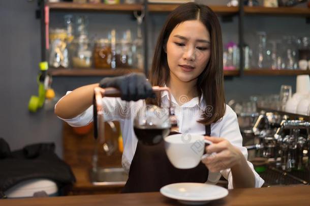 年幼的美丽的高加索人咖啡馆准备咖啡的员工传布咖啡豆和<strong>吸水</strong>管休假