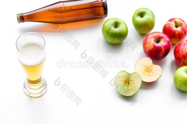 苹果苹果汁涌出进入中玻璃在近处瓶子和苹果.白色的背
