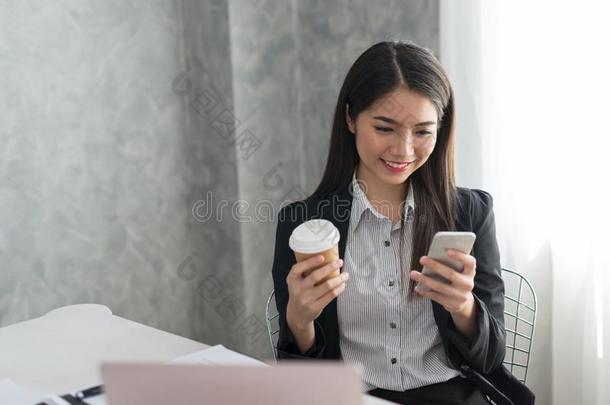 亚洲人商业女孩采用她工作站在hold采用g咖啡豆杯子和