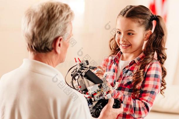 微笑的女孩有样子的在grandf在her佃户租种的土地机器人玩具
