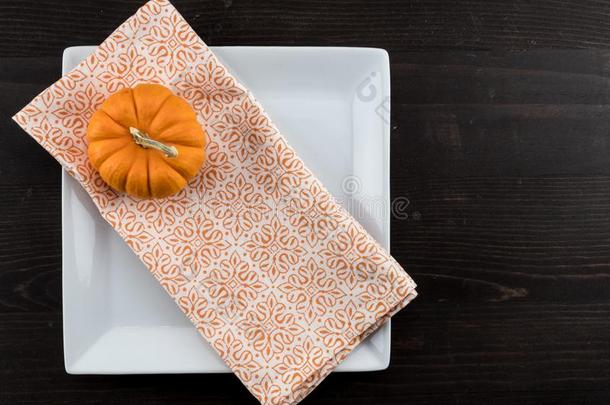 桔子餐巾和小的南瓜对角线向正方形盘子
