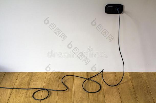黑的电的缆绳采用墙<strong>插座</strong>向木制的镶木地板地面