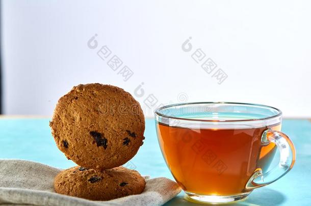 玻璃杯子关于茶水和燕麦片巧克力甜饼干关-在上面向蓝色