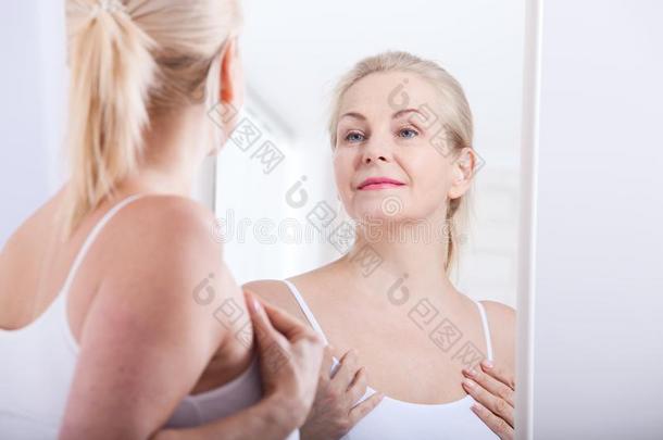 四十<strong>年</strong>老的女人有样子的在皱纹采用镜子.塑料制品在来自古法语的英语中与super-同义