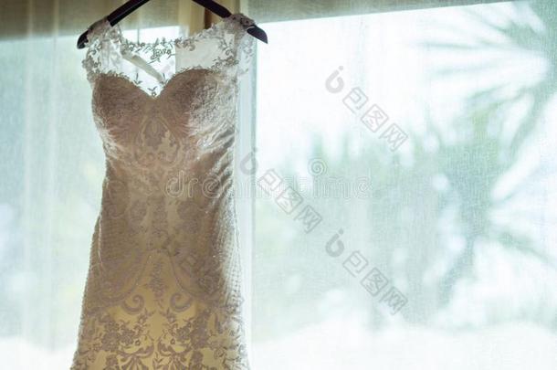白色的新娘衣服悬挂反对大的门或窗向白色的窗帘