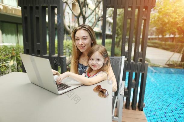 肖像关于母亲和女儿使用便携式电脑向背景关于游泳