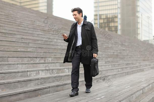 商业男人步行使用智能手机向注视pho向s.