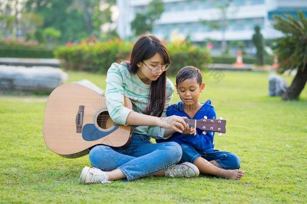 亚洲人十几岁的女孩教吉他为指已提到的人男孩和亲爱地和趺