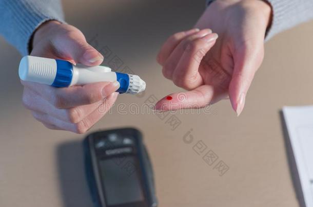 女人手使用<strong>柳叶</strong>刀向手指向检查血食糖水平