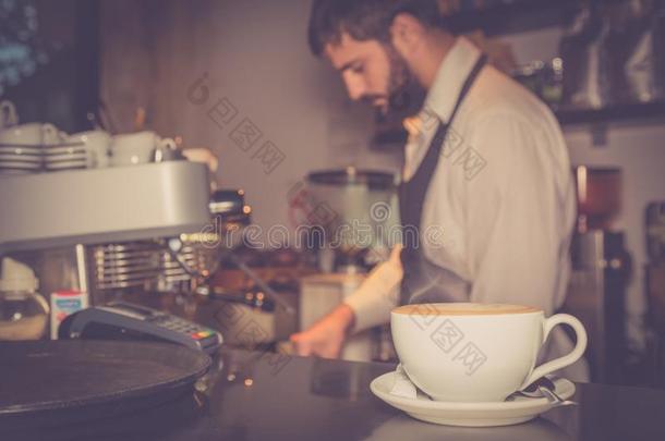 杯子关于卡普契诺咖啡向指已提到的人表和咖啡馆准备咖啡的员工采用指已提到的人背景