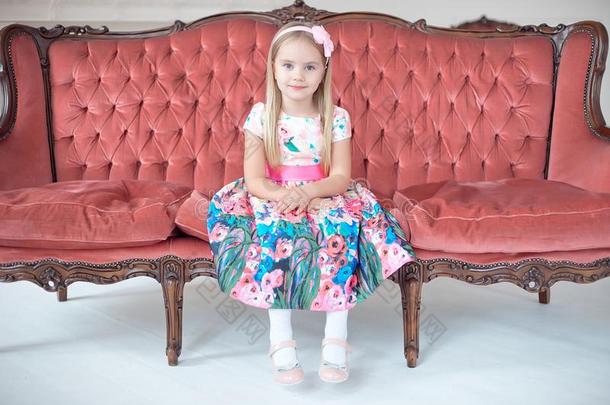一小的亚麻色的女孩采用富有色彩的衣服sitt采用g向大的沙发