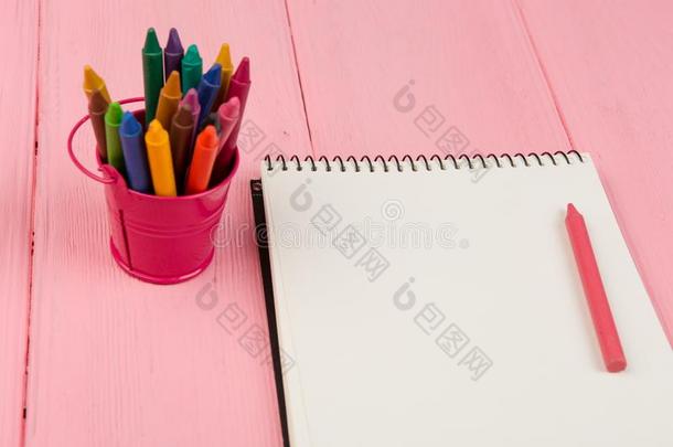 空白的便条簿和用彩色蜡笔画向粉红色的木制的表