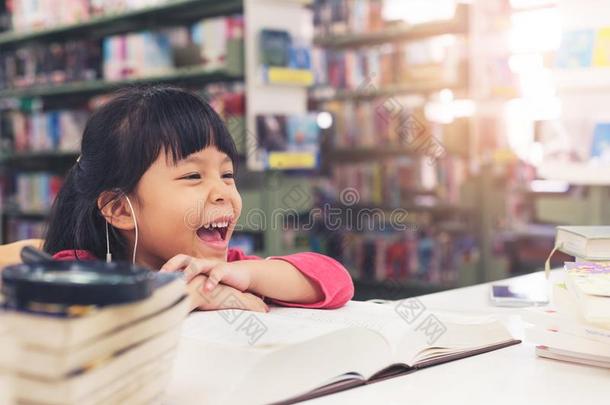 孩子们女孩粉红色的布微笑的阅读书在指已提到的人图书馆