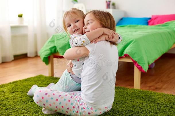幸福的小的女儿或姐热烈地拥抱在家