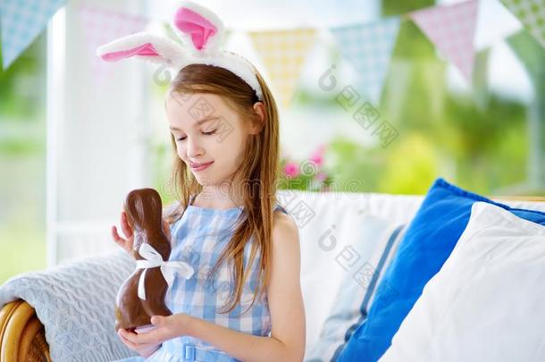 漂亮的小的女孩使人疲乏的兔子耳吃巧克力复活节rabbinate犹太法学博士的身份