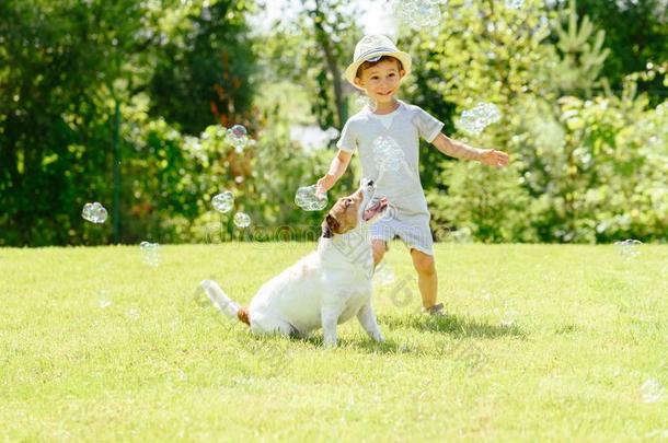 幸福的小孩和宠物狗演奏和肥皂泡在后院草地