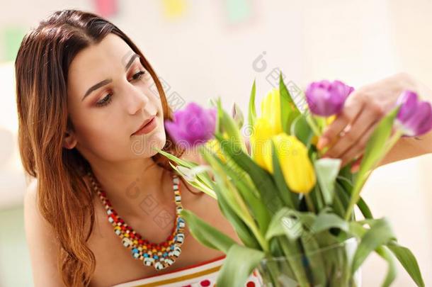 有魅力的女人安排郁金香花采用装饰瓶