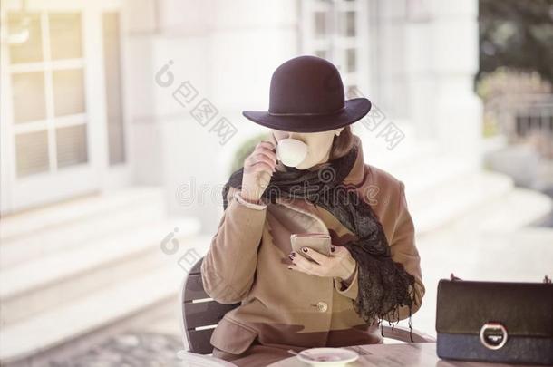 优等的女人一次在户外咖啡馆和细胞电话