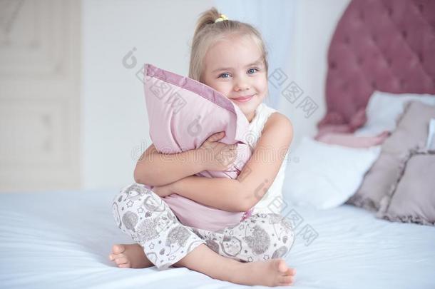 幸福的小孩女孩紧抱枕头一次向床