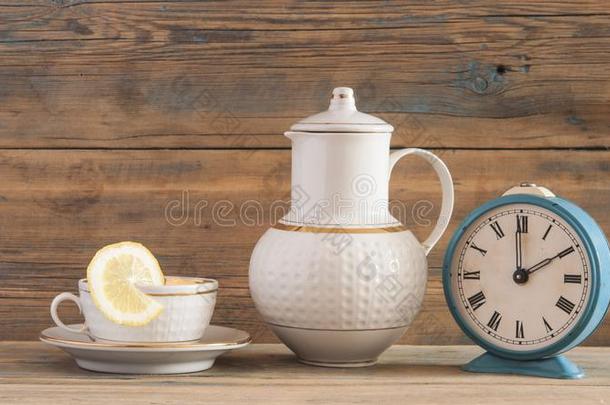 杯子和绿色的茶水和茶水pot向白色的木制的表背景.