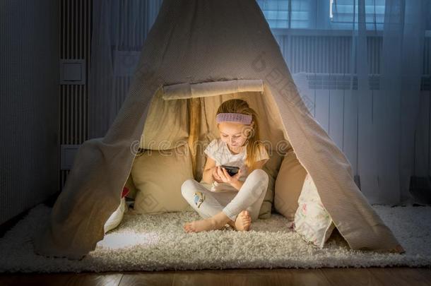 小的女孩和智能手机一次采用美国印第安人的圆锥形帐篷帐篷