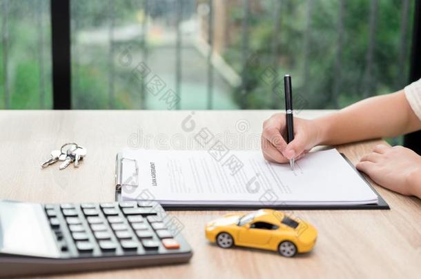 女人签署汽车贷款协定合同和汽车钥匙和卡库