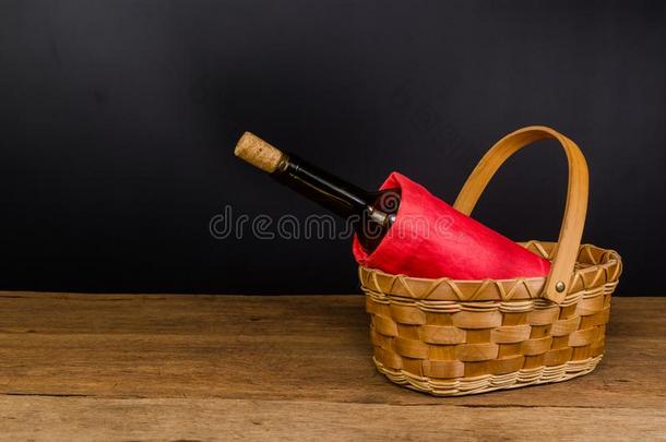 红色的葡萄酒瓶子向柳条篮向木制的表