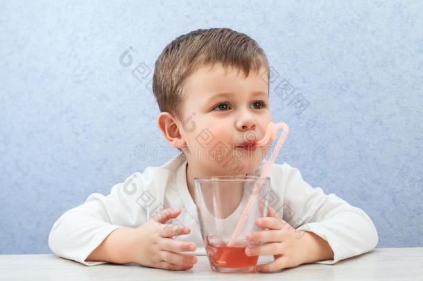 漂亮的小的男孩喝饮料果汁向光<strong>蓝色背景</strong>.<strong>可爱</strong>的