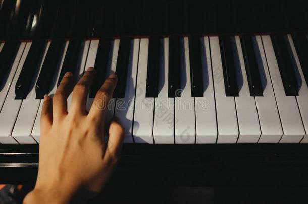 年幼的女人使用左边的手比赛钢琴有钢琴钥匙是后座