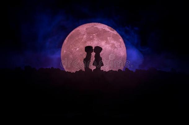 轮廓关于对接吻的在下面满的月亮.家伙接吻女孩手