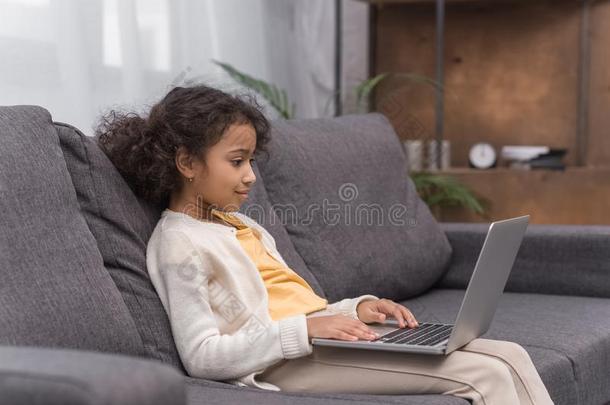 非洲的美国人<strong>小孩</strong>使用便携式<strong>电脑</strong>向沙发在家