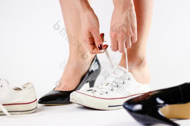 女孩替换鞋子.开除黑的鞋子和穿着白色的橡皮底帆布鞋