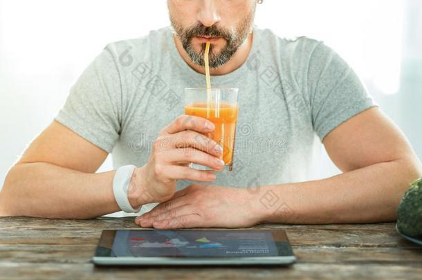 集中的可爱的男人有样子的在指已提到的人便携式电脑喝饮料果汁.