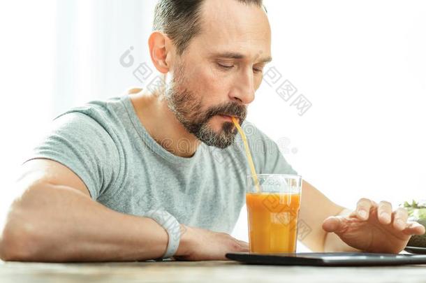 镇定的已占用的男人喝饮料果汁和使用指已提到的人碑.