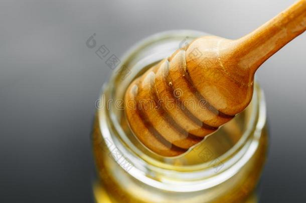 蜂蜜罐子和浸渍者和流动的蜂蜜