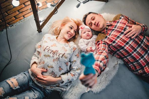 妈妈,爸爸和婴儿躺向一羊毛制的c一rpet和微笑