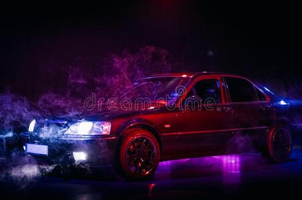 奢侈酿酒的黑色亮漆汽车和红色的和蓝色照明和雾