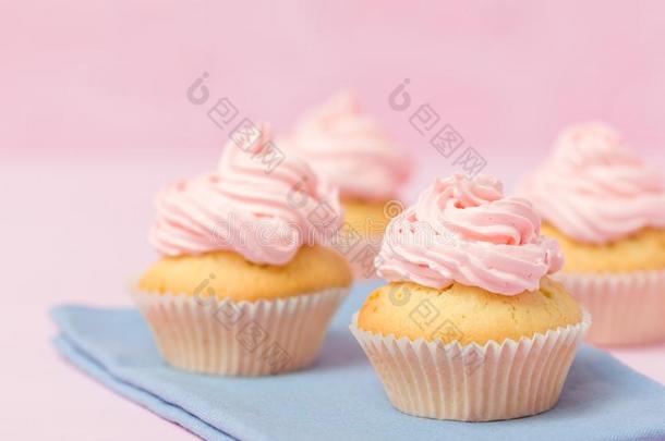 纸杯蛋糕装饰和粉红色的甜奶油酱向彩色粉笔粉红色的后座