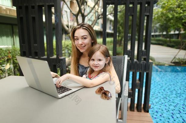 肖像关于母亲和女儿使用便携式电脑向背景关于游泳
