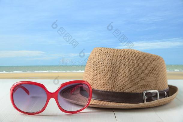 红色的太阳眼镜和时尚帽子向海和蓝色天背景