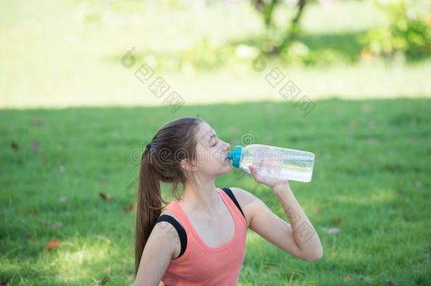 美丽的年幼的女运动家喝水在指已提到的人公园后的普拉克蒂