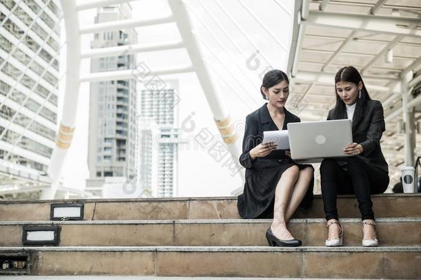 两个商业女人坐向指已提到的人楼梯和说话关于商业