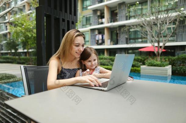 美丽的母亲和女儿使用便携式电脑向背景关于游泳