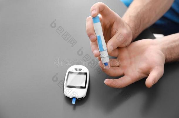 糖尿病的男人使用柳叶刀笔和数字的血糖测计仪