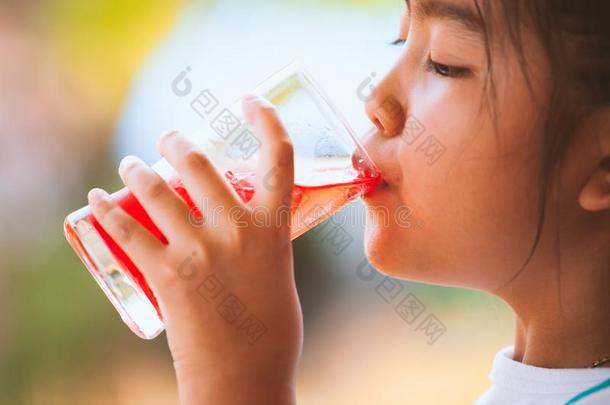 漂亮的亚洲人小的小孩女孩喝饮料红色的果汁水