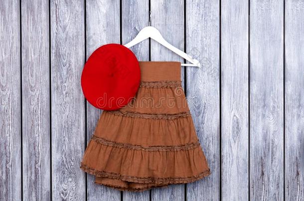 平的放置棕色的裙子和红色的帽子向指已提到的人表.